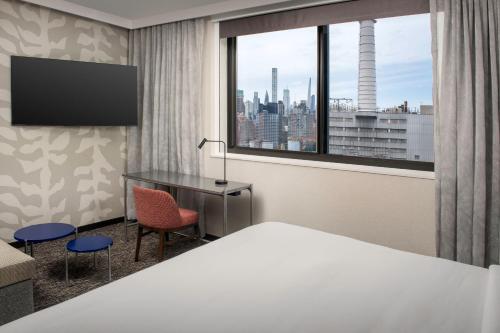 a hotel room with a bed and a desk and a window at Residence Inn by Marriott New York Queens in Queens