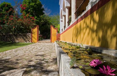 a building with a pond with pink flowers on it at Hacienda San Jose Cholul in Tixkokob