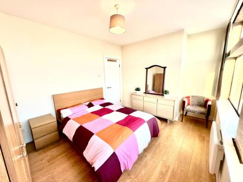 ein Schlafzimmer mit einem Bett, einem Spiegel und einem Stuhl in der Unterkunft Two Bedroom apartment with Kitchen Facility in Manchester