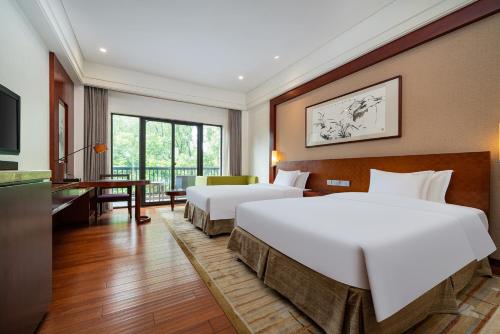 een hotelkamer met 2 bedden en een bureau bij Holiday Inn Resort Chaohu Hot Spring, an IHG Hotel in Chaohu