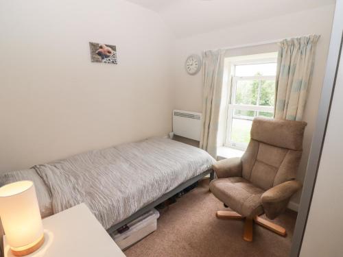 a bedroom with a bed and a chair and a window at Daffodil Apartment in Tenby