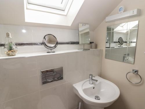 a white bathroom with a sink and a mirror at Daffodil Apartment in Tenby