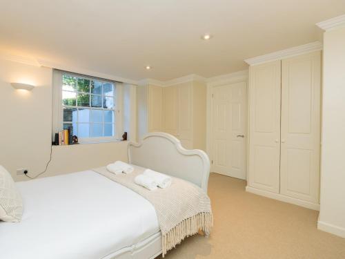 een witte slaapkamer met een wit bed en een raam bij Pass the Keys Stunning garden flat with parking in Bath