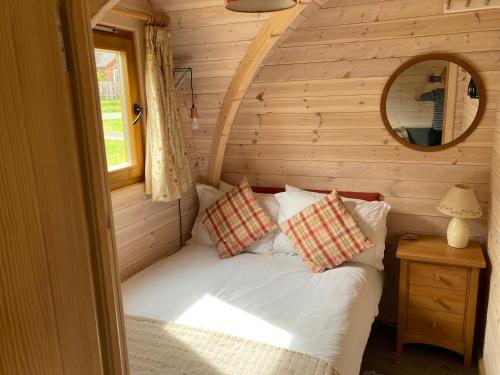 a bedroom with a bed in a log cabin at Rabbit Glamping Pod School House Farm in Leighton