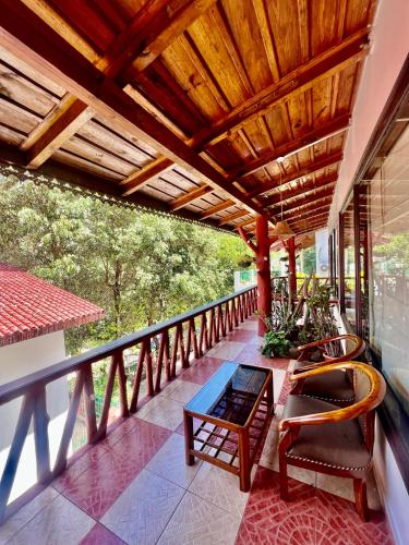 a balcony with a wooden roof with chairs and a table at Sea Hawk - Luxury Hill Resort 4 mins from Bhimtal Lake in Bhīm Tāl