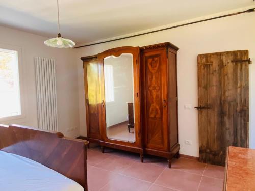 a bedroom with a mirror and a wooden cabinet at Relaxing house with exclusive swimming pool, close to Imola and Faenza, 4 bathrooms in San Mauro