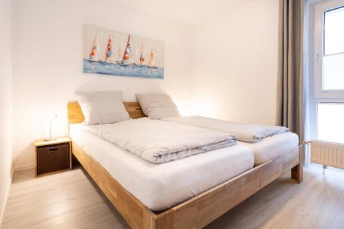 una camera da letto con un grande letto con lenzuola bianche di Ostseeresidenz App 22 a Heiligenhafen