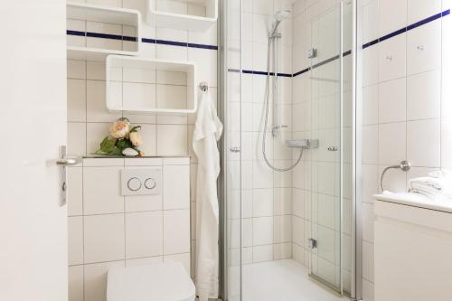 ein weißes Bad mit einer Dusche und einem WC in der Unterkunft Ostseeresidenz App 22 in Heiligenhafen