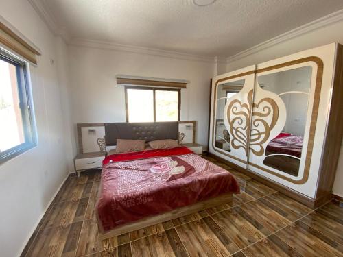 - une chambre avec un lit et un grand miroir dans l'établissement Jar AlQamar Chalet -شاليه جار القمر, à Jerash