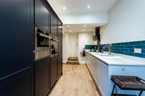 a kitchen with black appliances and blue tiles at Tyne Square North Shields - historic property - dog friendly in North Shields