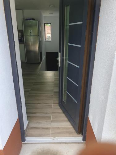 a hallway with an open door and a hallway with a refrigerator at Vila AliBi Valiug - 200m from Ponton Casa Baraj in Văliug