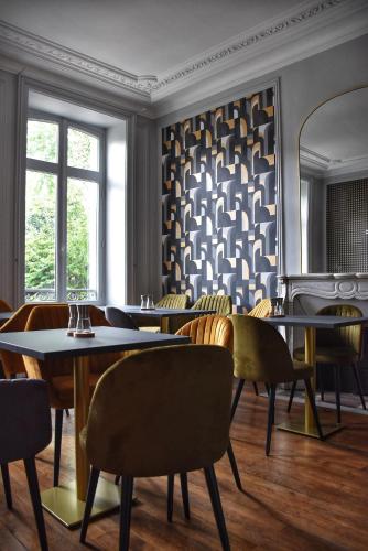 un restaurant avec des tables et des chaises et un mur à motifs dans l'établissement La maison de famille Limoges, à Limoges