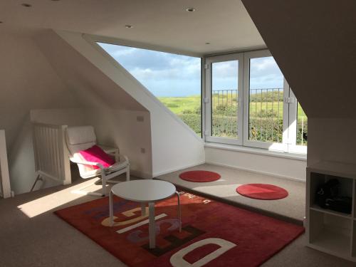 una camera con una sedia, un tavolo e una finestra di Golf View Cottage PORTRUSH a Portrush