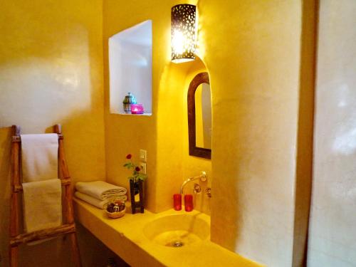 a yellow bathroom with a sink and a mirror at Les Jardins de Skoura in Skoura