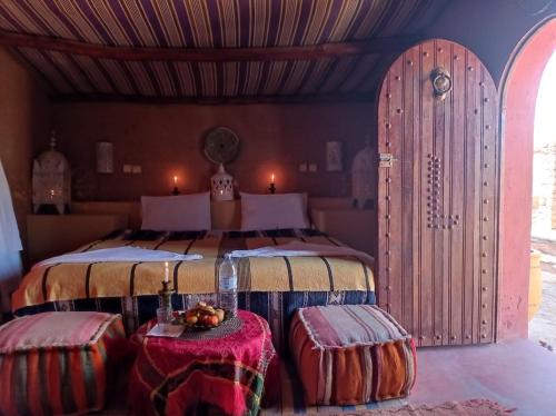 una camera da letto con un letto con due tavoli davanti di Desert Bivouac Mhamid a M'Hamid