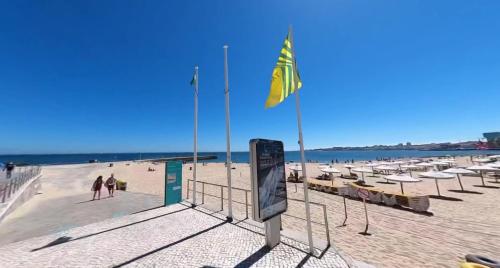 a beach with chairs and a yellow flag on it at Estoril Casino 3 Bedrooms With Pool in Estoril