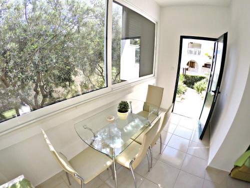 a glass table and chairs in a room with windows at Apartments Vanja in Omiš