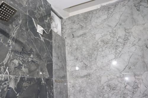 e bagno con parete in marmo e doccia. di HOTEL THE GRAND MARUTI a Junagadh
