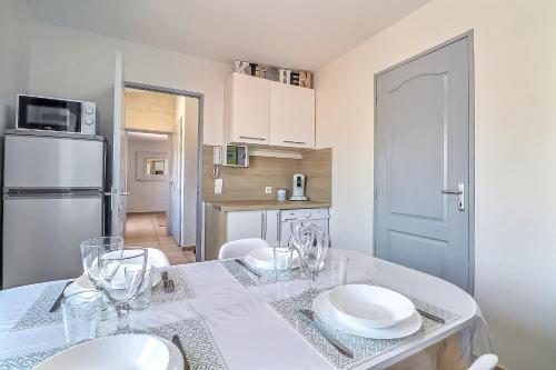 a kitchen with a table with plates and glasses on it at LE TOLOSANA - Appartement 4 personnes - Centre WiFi Cosy in Saint-Gilles