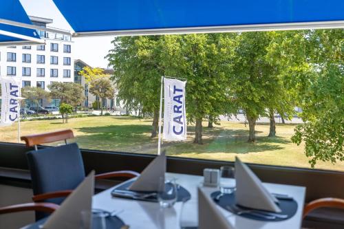 Un restaurante con mesas y sillas con vista a un parque. en Carat Hotel Grömitz, en Grömitz