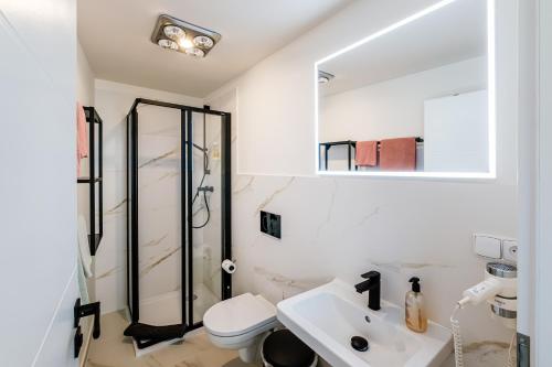 a white bathroom with a shower and a sink at VV hotel & apartments in Brno