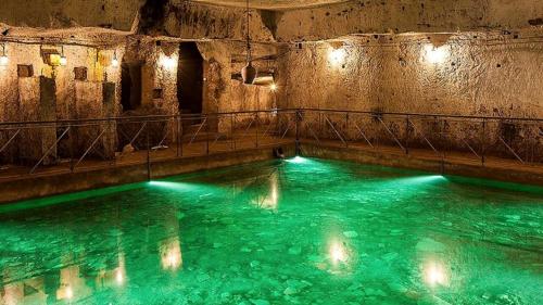 una piscina de agua verde en una cueva en Archihouse Suites en Nápoles