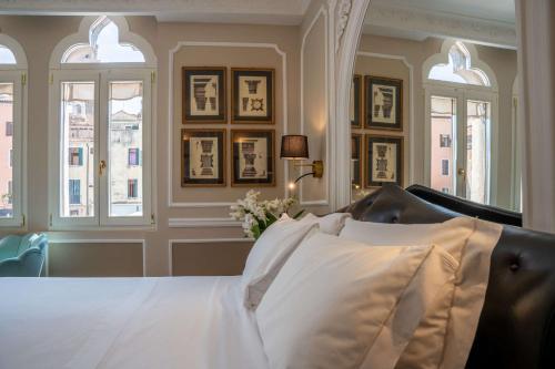 a bedroom with a bed with white sheets and windows at Hotel Santo Stefano in Venice