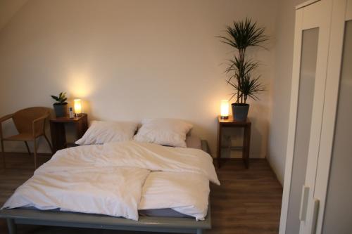 um quarto com uma cama com lençóis brancos e duas luzes em Messe- und Gästezimmer Hildesheim em Harsum