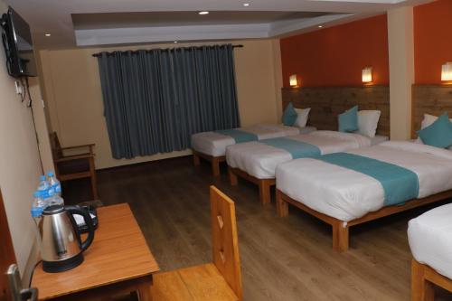 een hotelkamer met vier bedden en een tafel bij Peshal Home in Kathmandu