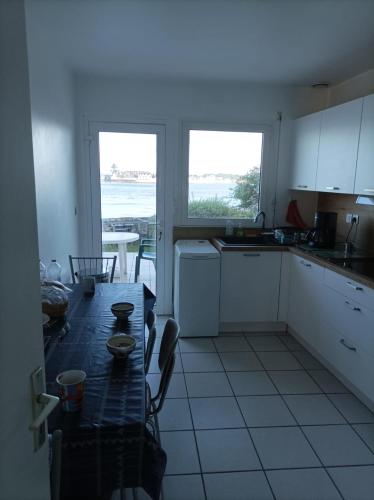 une cuisine avec une table et une vue sur l'océan dans l'établissement “Maison en bord de mer à Loctudy avec vue sur le jardin.