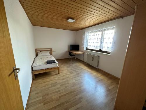 1 dormitorio con cama, escritorio y ventana en HW1 Drei Zimmer Wohung 80qm, en Königsbronn