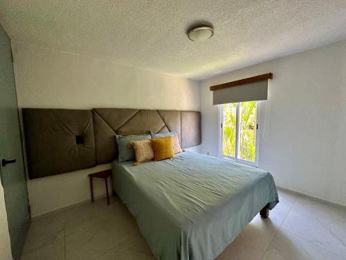 a bedroom with a bed and a window at CORMORAN COZY CONDO IN IXTAPA in Ixtapa
