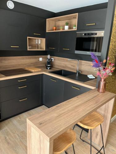 a kitchen with black cabinets and a wooden counter top at COCON NOELY 1 in Toulouse