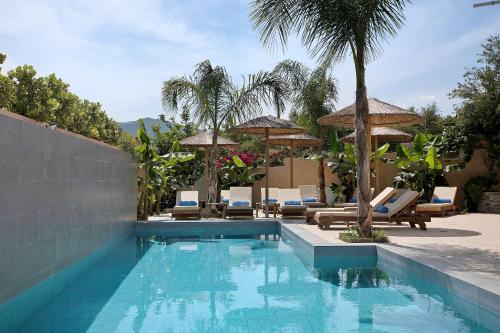 a swimming pool with lounge chairs and umbrellas at Villa Dionysia Apartment A2 in Alikanas