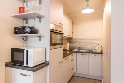 a kitchen with white cabinets and a microwave at Sandwig-Lodge in Glücksburg
