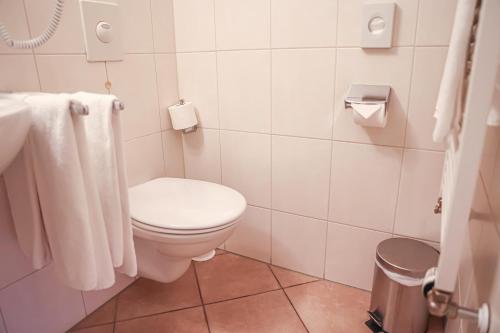 a bathroom with a toilet and a sink and towels at Hotel-Gasthaus Goldener Engel in Glottertal