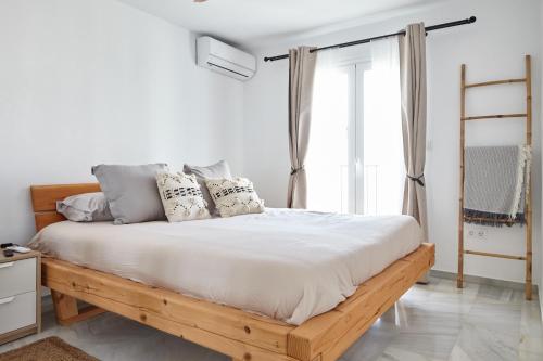 a white bedroom with a wooden bed with pillows at Casa Sierra - Mijas Pueblo in Mijas