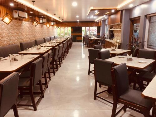 a dining room with long tables and chairs at Hotel Satkar in Katihār