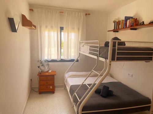 een slaapkamer met 2 stapelbedden en een raam bij Apartament a Pals, amb piscina, platja a 1 minut in Pals