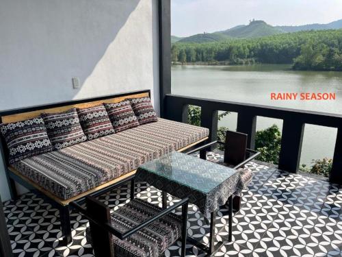 Nguyen Shack - Phong Nha Resort في فونغ نها: شرفة مع أريكة وطاولة وإطلالة على نهر