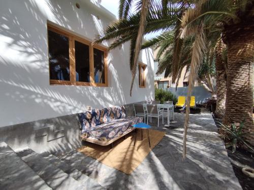 a patio with a couch and a table and a palm tree at La Casita a 60 pasos del mar in Tamaduste