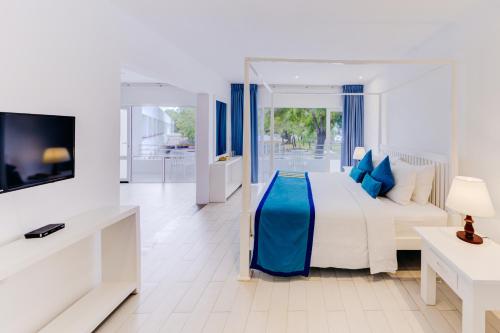 a white bedroom with a bed and a tv in it at Trinco Blu by Cinnamon in Trincomalee