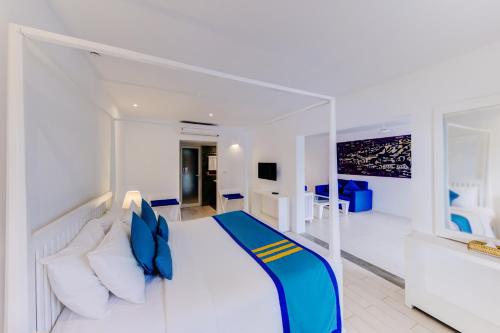 a bedroom with a large white bed with blue pillows at Trinco Blu by Cinnamon in Trincomalee