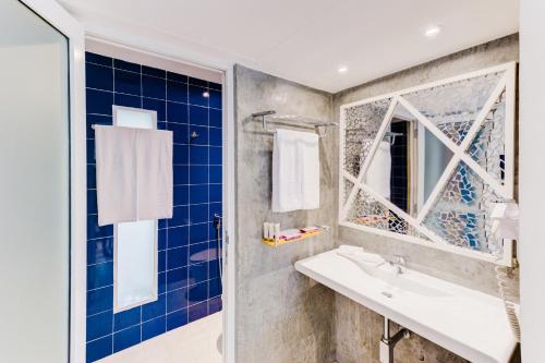 a bathroom with blue tiles and a sink and a window at Trinco Blu by Cinnamon in Trincomalee