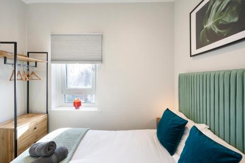 a bedroom with a bed with blue pillows and a window at Cosy Modern Apartment With Free Parking in Cardiff