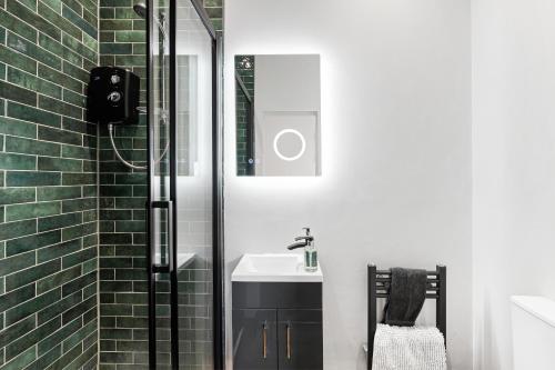 uma casa de banho com um chuveiro e um lavatório branco em Cosy Modern Apartment With Free Parking em Cardiff