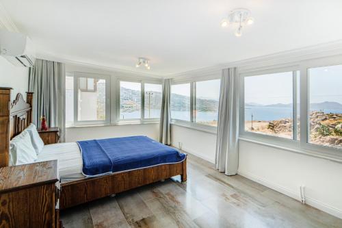 a bedroom with windows and a bed with a blue blanket at Villa w Pool Garden Patio 1 min to Beach in Bodrum in Yalıkavak
