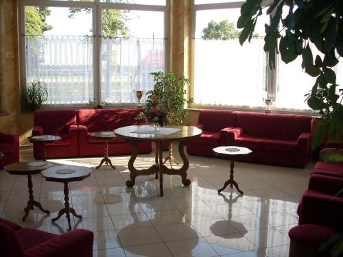 a living room with red couches and tables and windows at Il Bivio Hotel in Carmagnola