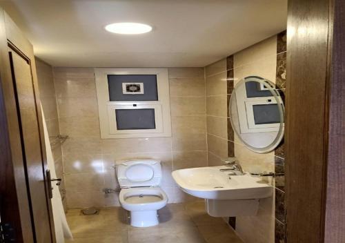 ein Badezimmer mit Toilette, Waschbecken und Spiegel in der Unterkunft Spacious 2Bdrs duplex in Porto new Cairo in Kairo