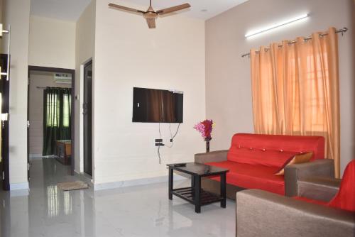 a living room with a red couch and a table at Private 4 BHK Villa with WiFi, Swimming Pool, BBQ in Chennai